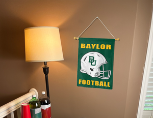 Green 13x18 inch long Baylor University Football Garden Flag hanging on a banner pole covering the well-lit living room brown wall