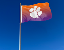 Load image into Gallery viewer, Gradient 3x5 feet wide Clemson University Flag with two metal grommets attached to flagpole waving in the wind
