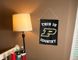 purdue garden flag with this is p country logo hung on a banner pole next to a lamp and drinks