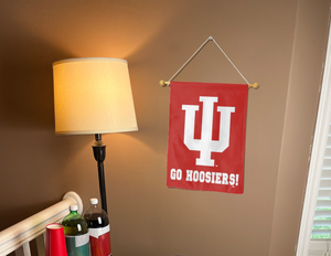 red indiana university garden flag with go hoosiers logo hanging on banner pole inside living room