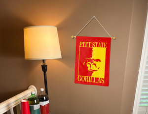 red Pittsburg state university garden flag hanging on banner pole inside room