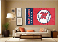 Load image into Gallery viewer, two panel blue and red Ole Miss Baseball Flag with two metal grommets covering tan wall of well lit room
