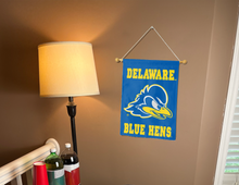Load image into Gallery viewer, blue University of Delaware Garden Flag hung from banner pole inside living room
