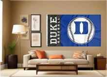 Load image into Gallery viewer, Blue and Black 3x5 Duke Baseball Flag with two metal grommets covering tan wall of well lit room
