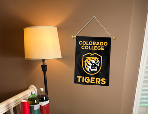 black colorado college garden flag hung from banner pole inside a room