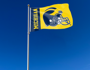 3x5 foot wide University of Michigan Football Flag with two metal grommets attached to flagpole waving in the wind