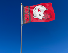 Load image into Gallery viewer, Red 3x5 University of Nebraska Football Flag with two metal grommets attached to flagpole waving in the wind
