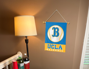 Blue and gold UCLA Baseball Garden Flag hanging on banner pole inside living room