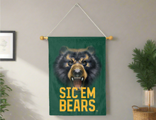 Load image into Gallery viewer, Green 30x40 inch long Baylor University House Flag with Realistic Bear Eyes and Sic Em Bears Logo hanging on a banner pole covering the grey living room wall

