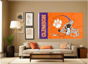 Orange and Purple striped 3x5 foot wide Clemson University Football Flag with two metal grommets covering the tan wall inside of a well organized room with couch pillows and light