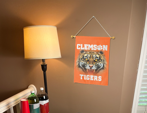 Orange Clemson University Garden Flag with Realistic Tiger Eyes Logo hung from banner pole inside the living room