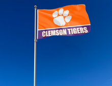Load image into Gallery viewer, 3x5 feet wide Clemson University Tigers orange and Purple stripes with Clemson Tigers Logo and two metal grommets attached to flagpole waving in the wind
