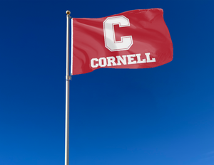 Red 3x5 foot wide Cornell University Flag with white C Cornell logos and two metal grommets attached to flagpole waving in the wind