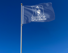 Load image into Gallery viewer, Blue 3x5 foot wide Duke University Flag with Duke Logo Blue Devils Logo and two metal grommets attached to flagpole waving in the wind
