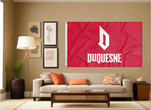 Load image into Gallery viewer, Red 3x5 foot wide Duquesne University Flag with white D Duquesne logo and two metal grommets covering the tan wall of the living room
