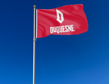 Load image into Gallery viewer, Red 3x5 foot wide Duquesne University Flag with white D Duquesne logo and two metal grommets attached to flagpole waving in the wind
