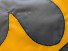 Load image into Gallery viewer, Close-up of a black, hand-sewn Iowa Hawkeyes logo on a gold university of iowa applique flag
