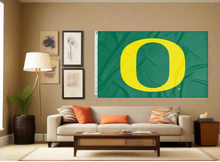 Load image into Gallery viewer, Green University of Oregon Flag hung inside a well-lit room above a sofa
