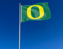 Load image into Gallery viewer, Green University of Oregon Flag attached to flagpole waving in the wind
