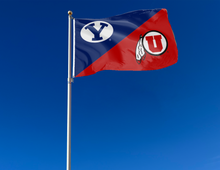 Load image into Gallery viewer, blue and red BYU Utah House Divided Flag with two metal grommets attached to flagole waving in the wind
