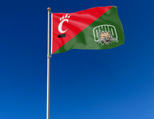 Load image into Gallery viewer, red and green Cincinnati Ohio University house divided flag attached to flagpole waving in the wind
