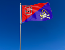 Load image into Gallery viewer, red and purple NC State ECU house divided flag attached to flagpole waving in the wind
