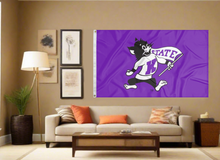 Load image into Gallery viewer, Purple 3x5 foot wide Kansas State University Flag with Willie the Wildcat mascot logo and two metal grommets covering tan wall of a well-lit room
