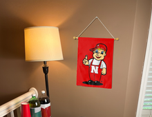 Load image into Gallery viewer, lil red nebraska mascot garden flag hung from banner pole inside the living room
