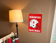 Load image into Gallery viewer, Red University of Nebraska Football Garden Flag hung from banner pole inside living room
