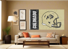 Load image into Gallery viewer, 3x5 feet wide Black and gold 2 panel University of colorado football flag with two metal grommets covering the tan wall inside of a well organized room with couch pillows and light
