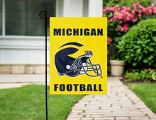 Load image into Gallery viewer, gold Michigan football logo garden flag hung on a garden flag stand outside
