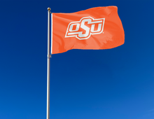 Load image into Gallery viewer, Orange 3x5 feet wide Oklahoma State University Flag with OSU Logo and two metal grommets for outdoor home decor attached to flagpole waving in the wind
