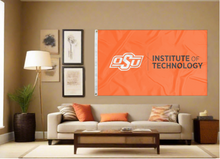 Load image into Gallery viewer, Orange Oklahoma State University Institute of Technology Flag with two metal grommets covering tan wall of well lit room
