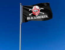 Load image into Gallery viewer, Black Nebraska Huskers flag with original blackshirts logo attached to flagpole waving in the wind
