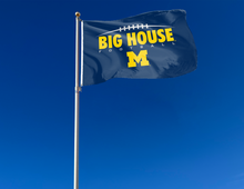 Load image into Gallery viewer, Blue 3x5 foot wide University of Michigan Flag with Big House Football M Logo and two metal grommets attached to flagpole waving in the wind
