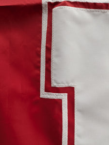 Close up shot of white hand-sewn nebraska huskers logo on red university of nebraska applique flag