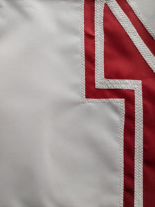 Close up shot of white hand-sewn nebraska huskers logo on red university of nebraska applique flag