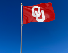 Load image into Gallery viewer, Red 3x5 feet wide University of Oklahoma Flag with two metal grommets for outdoor home decor attached to flagpole waving in the wind
