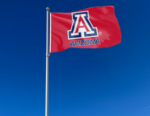 Red quadruple stitched flyends of 3x5 foot wide University of Arizona Flag with two metal grommets attached to flagpole waving in the wind for outdoor home decor