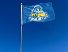 Load image into Gallery viewer, Blue 3x5 foot wide University of Delaware Flag with Blue Hens logo and two metal grommets attached to flagpole waving in the wind
