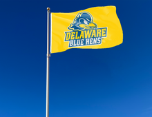 Load image into Gallery viewer, Gold 3x5 foot wide University of Delaware Blue Hens Flag with two metal grommets attached to flagpole waving in the wind
