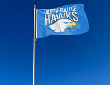 Load image into Gallery viewer, outdoor display of blue hilbert college hawks flag for tailgate decor
