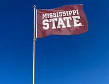 Load image into Gallery viewer, outdoor display of mississippi state university flag with mississippi state logo for tailgate decor
