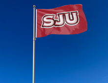 Load image into Gallery viewer, outdoor display of red saint joseph's university flag with sju hawks logo for tailgate decor
