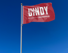 Load image into Gallery viewer, outdoor display of red university of indianapolis flag with uindy logo for tailgate decor

