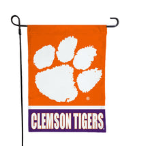 Load image into Gallery viewer, close-up shot of 13x18 inch long Clemson University Garden Flag with orange and Purple stripes and Clemson Tigers Logo hanging on a black garden flag stand

close-up shot of 13x18 inch long Clemson University Garden Flag with orange and Purple stripes and Clemson Tigers Logo hanging on a black garden flag stand
